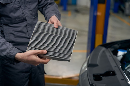 A cropped shot of a mechanic showing a clogged air filter during a vehicle inspection.