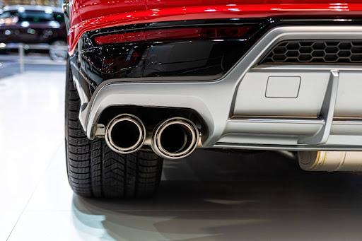 A clean, polished exhaust pipe of a red luxury car.