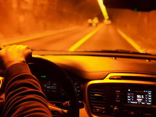 A man driving through a tunnel with an orange glow cast by his car’s headlights